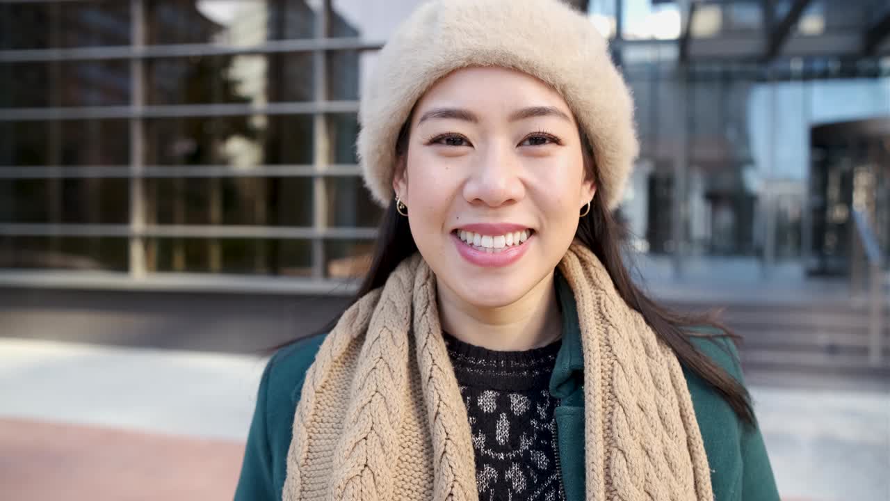 사무실 건물 밖에서 포즈를 취하는 동안 카메라를 보는 아시아 여성.