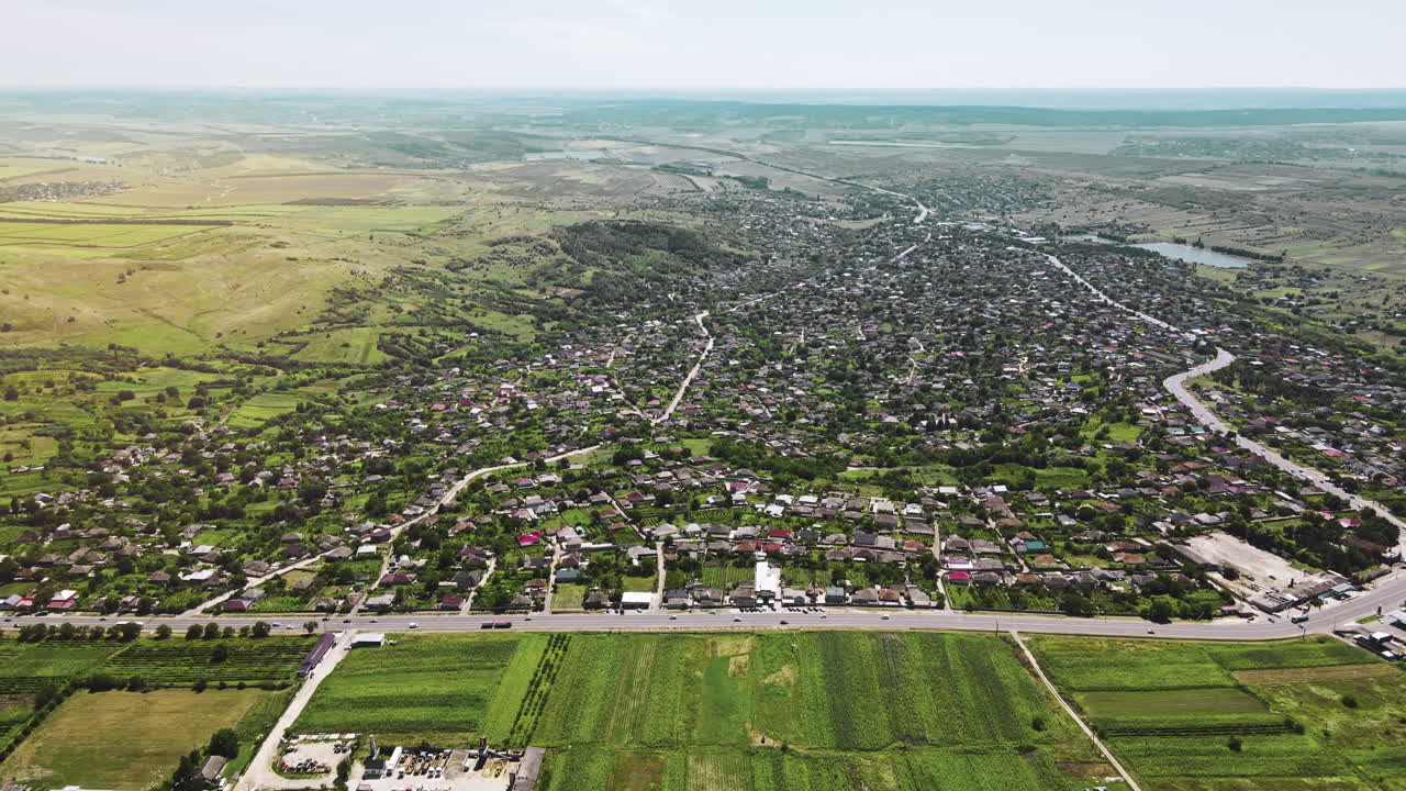 Aerial drone view of a village and road with cars. Greenery, hills and fields in Moldova