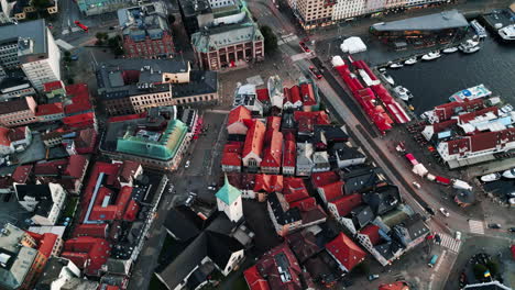 Aerial-view-over-residential-area-near-the-river,-boats-on-water,-car-traffic-on-roads,-colorful-rooftops,-captured-in-Bergen,-Norway