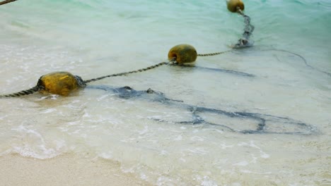 yellow buoys floating on waves near sandy beach in thailand