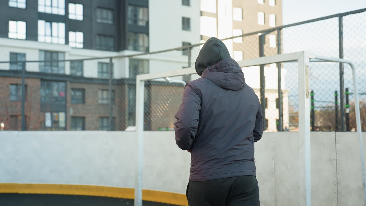 야외 스포츠 경기장에서 조하는 운동선수, 골포스트와 도시 고층 건물을 배경으로, 현대 도시 환경에서 활발한 생활 방식, 결단력 및 피트니스를 강조합니다.