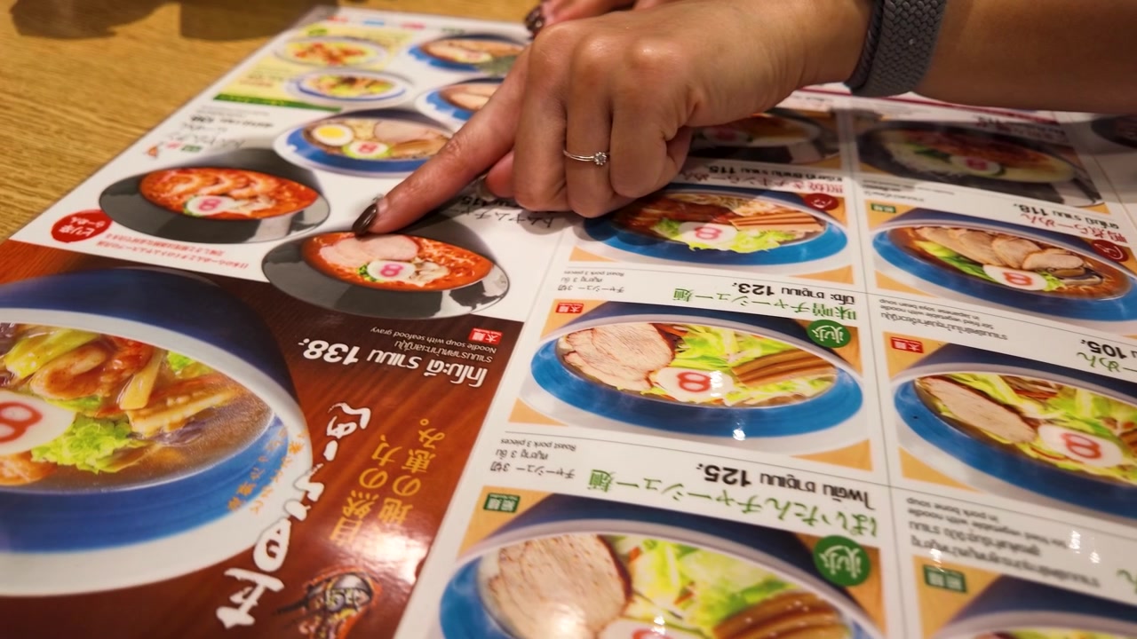 Person peker på ramen-alternativer på en restaurantmeny