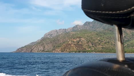 remote tropical island coastline seen from boat travel, behind the seat, arriving at atauro island in timor leste, southeast asia