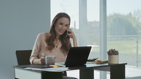 mujer de negocios trabajando en una computadora portátil. mujer concentrada hablando por teléfono.