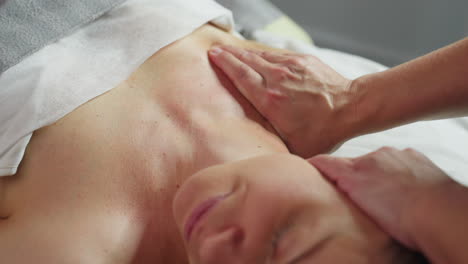 bodywork therapist smooths client chest and neck using slow circular fingertip motions during relaxing spa treatment in bright clinical room with soft linens and precise gentle pressure