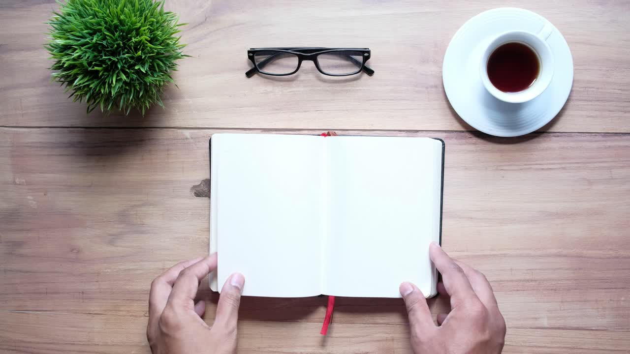 Open Notebook on a Wooden Desk with Coffee and Glasses