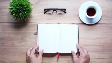 open notebook on a wooden desk with coffee and glasses