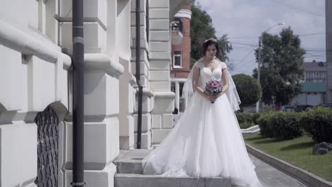slow-motion-bride-in-wedding-dress-stands-near-building