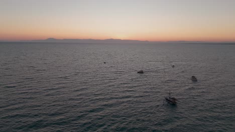 Gruppe-Kleiner-Boote,-Die-Gemeinsam-Auf-Dem-Mittelmeer-In-Richtung-Des-Leuchtenden-Sonnenuntergangshorizonts-Segeln