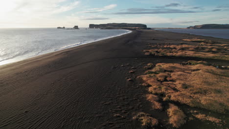 Playa-De-Arena-Negra-Cubierta-De-Musgo-En-Islandia-Durante-La-Toma-Aérea-Del-Establecimiento-Del-Atardecer.