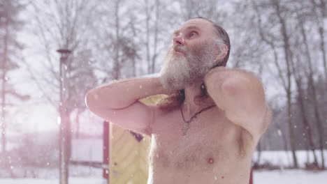 scraggy man in falling snow loses himself in skyward meditation after sauna