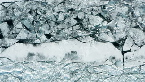 aéreo de arriba hacia abajo, capa de hielo delgada agrietada causada por el calentamiento global