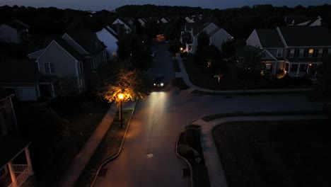 tranquil american neighborhood at night with driving car along street with orange lantern light