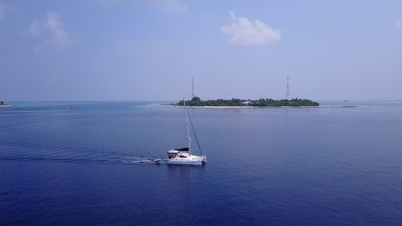 yate navegando lentamente alrededor de islas tropicales en un mar azul tranquilo al amanecer con un cielo brumoso en un hermoso paisaje marino de maldivas
