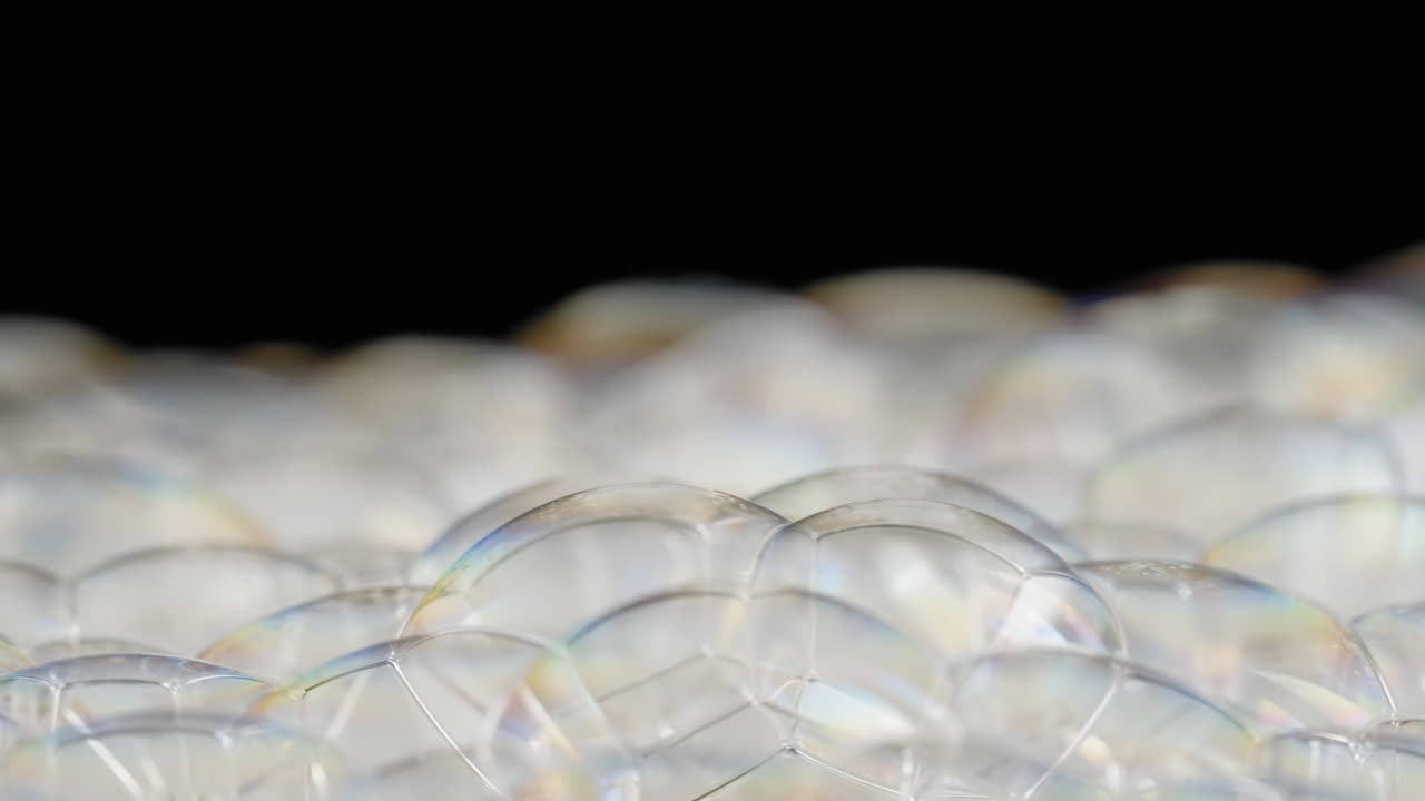 검은 바탕에  ⁇ 어 나오는 회전하는 비누 거품의 클로즈업