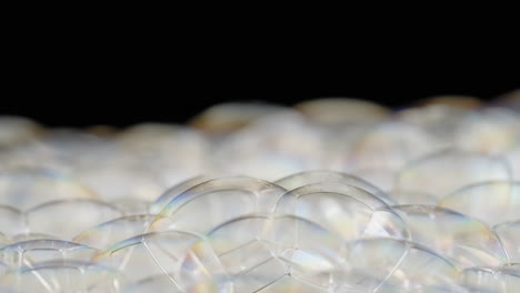 close-up of spinning soap bubbles popping against black background