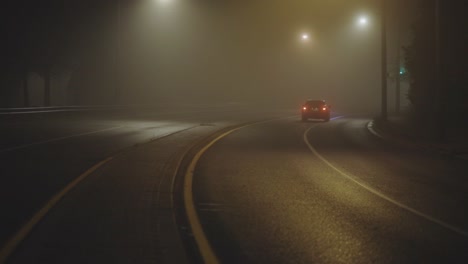 rear view of car in motion on country road on foggy night - wide