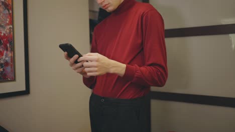 caucasian man using cellphone while standing inside a room - medium shot