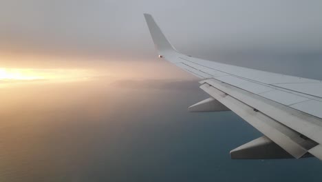 a stunning sunset seen from the airplane window looking over plane wing, land and ocean of new zealand aotearoa