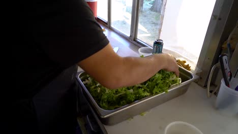 a food worker grabs greens