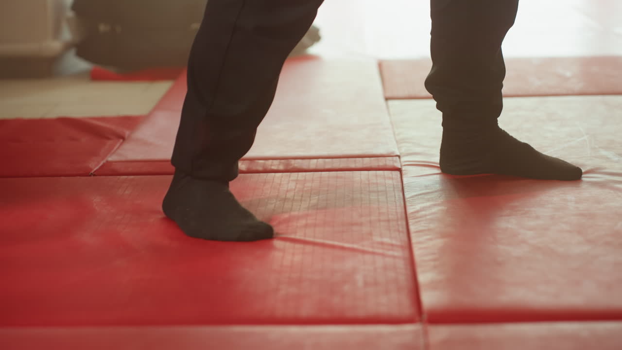 Boxer footwork on red gym mat showing precise stance, balance, coordination, and agility during combat training, emphasizing movement, posture, rhythm, and physical control essential for martial arts