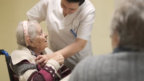 disabled senior woman talking to caregiver in canteen at nursing home