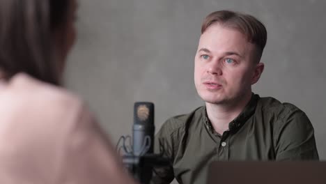 couple of male and female radio hosts or podcasters speak into a microphone with headphones create audio content in the studio or on the radio on the air