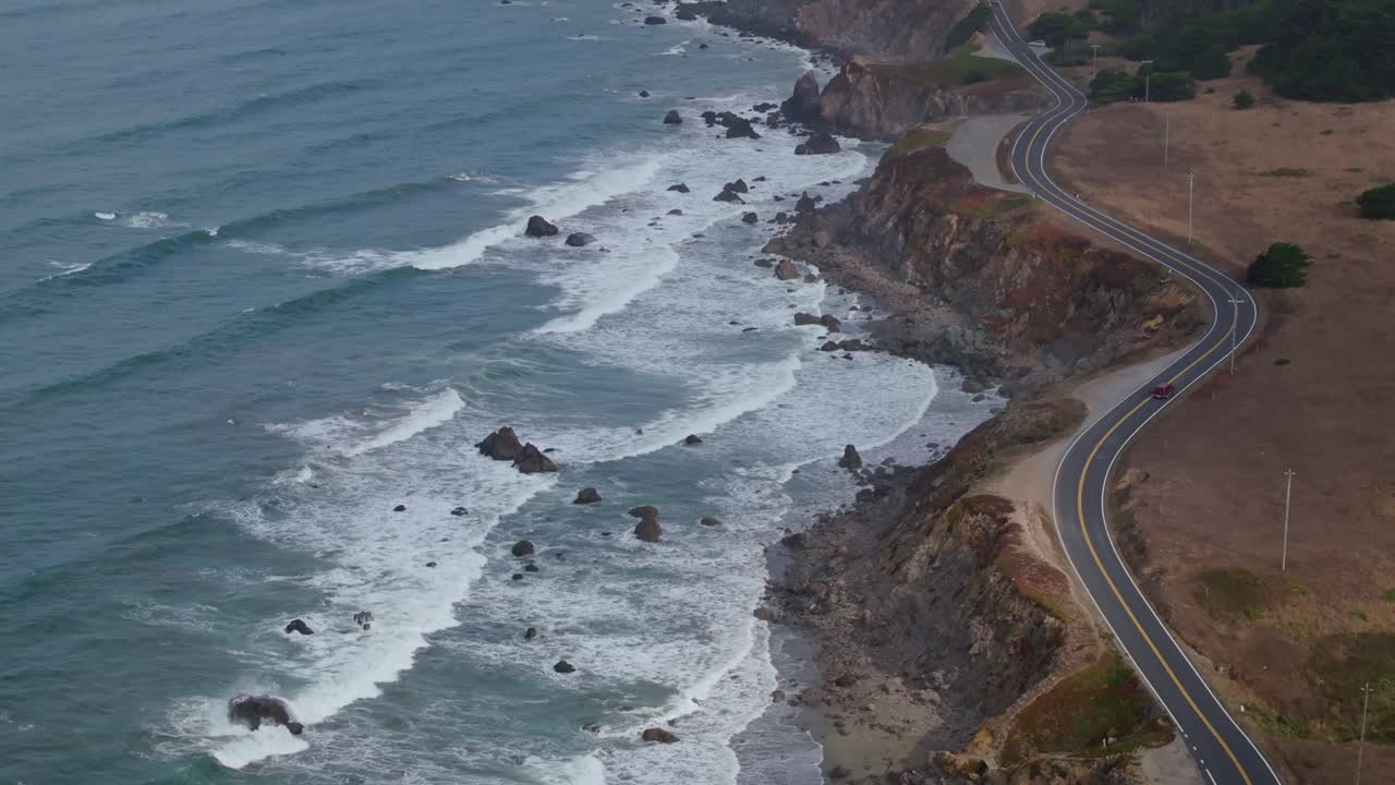 Waves crash along the rugged California coast on a cloudy day