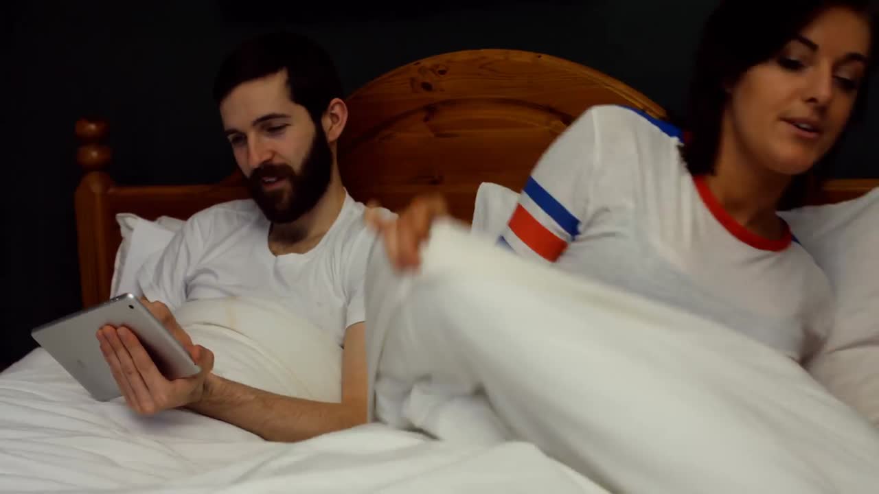 Couple using digital tablet on bed in bedroom