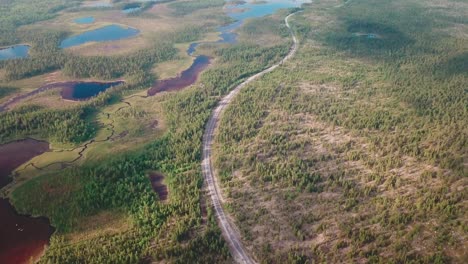 Toma-Aérea-De-ángulo-Alto-Hacia-Adelante-De-Un-Bosque-Con-Lagos-Y-Una-Carretera-Al-Norte-De-Finlandia