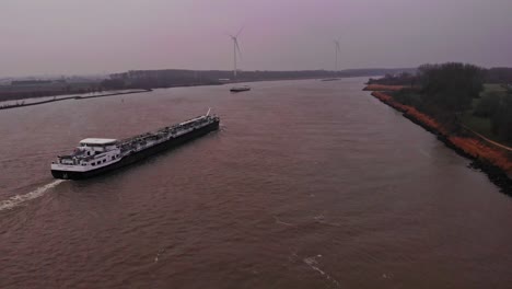 aerial view of tanker ship travelling along oude maas on overcast day