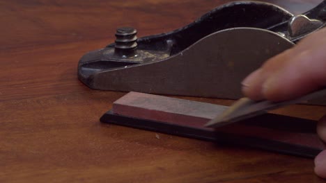 blade from antique vintage wood plane is sharpened on a whetstone