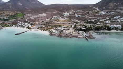 aerial panning shot over the beach of playa el caymancito near la paz baja california sur mexico overlooking the beach, dry landscape with hotel resorts during a great trip