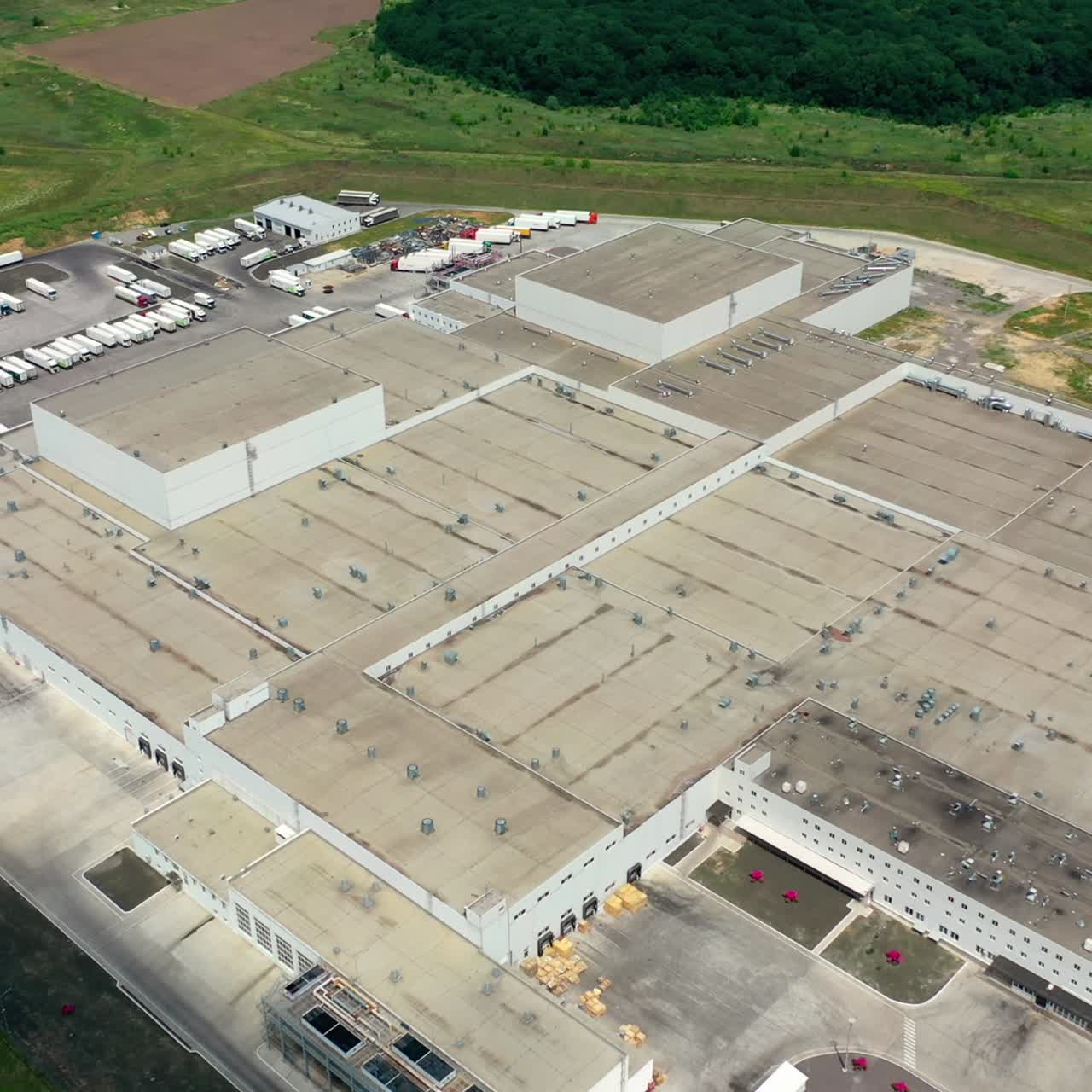 Large factory on green field. Flying over industrial plant. Exterior of white buildings of large industrial complex. Aerial view