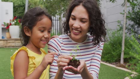Hispanische-Mutter-Und-Tochter-Unterrichten-Das-Pflanzen-Von-Blumen-Im-Garten