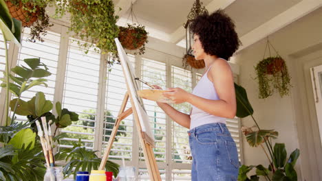 painting on canvas, woman holding palette and brush in bright room