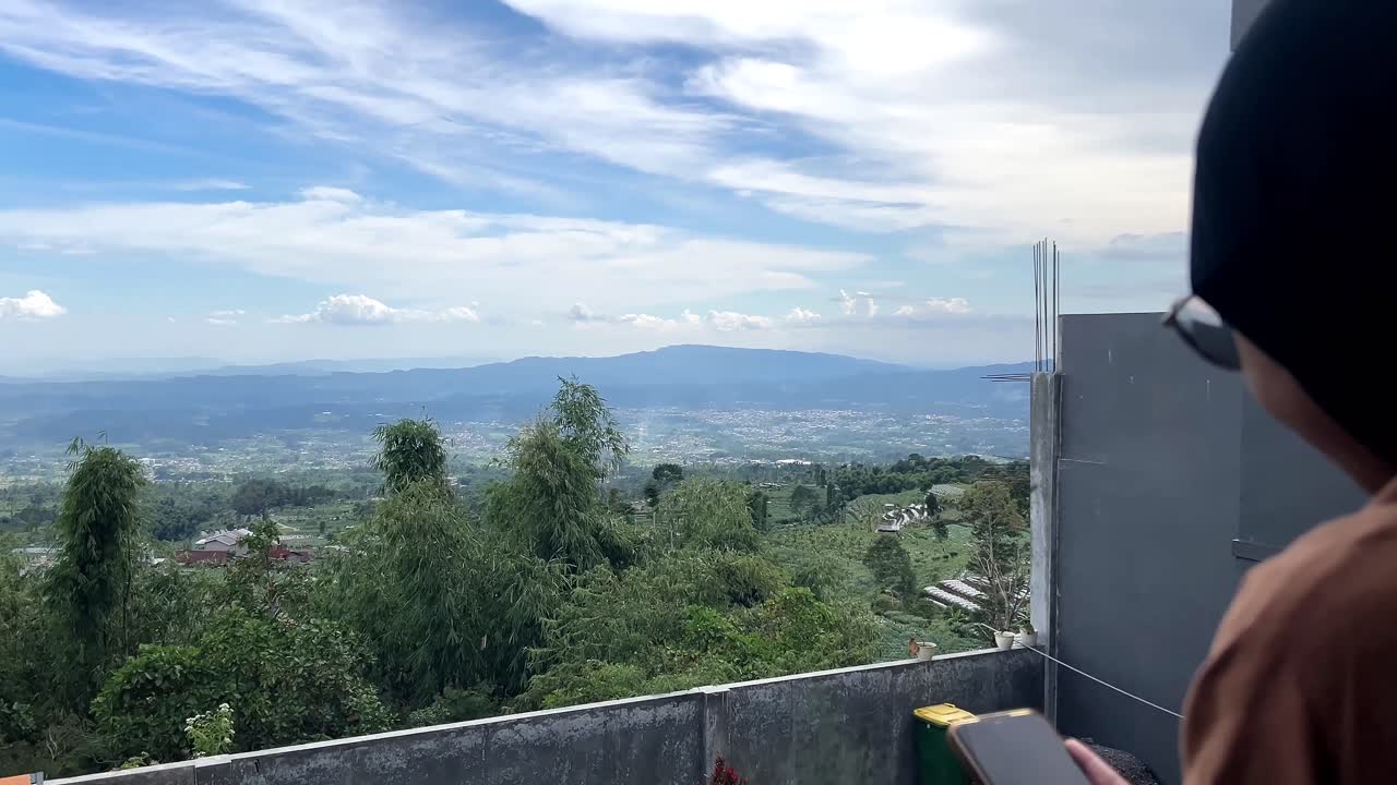 Enfoque selectivo de una mujer musulmana usando un smartphone a un hermoso paisaje montañoso.