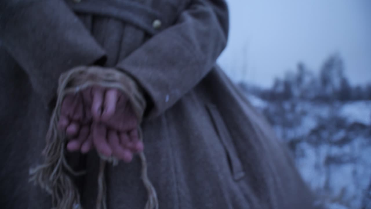 Cinematic close up of a prisoner's hands tied firmly with a rope behind their back while wearing a vintage wool coat in a freezing snowy winter landscape