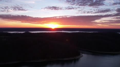 Brillanter-Sonnenaufgang-über-See-Und-Bäumen-Mit-Wolkenbewegung