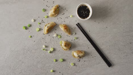 Composition-of-gyoza-dumplings-and-soy-sauce-with-chopsticks-on-grey-background