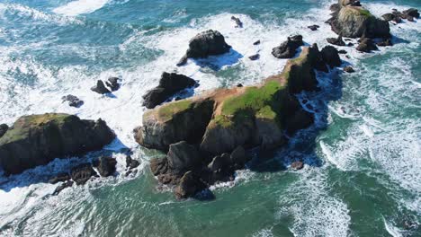 Wunderschöne-4K-Luftdrohnenaufnahme-Von-Meereswellen,-Die-In-Bandon,-Oregon,-Gegen-Felsen-Krachen,-Mit-Mohnblauem-Himmel-Im-Hintergrund