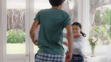 happy father dancing with teenage daughter having fun enjoying playful dance enjoying weekend celebration at home wearing pajamas