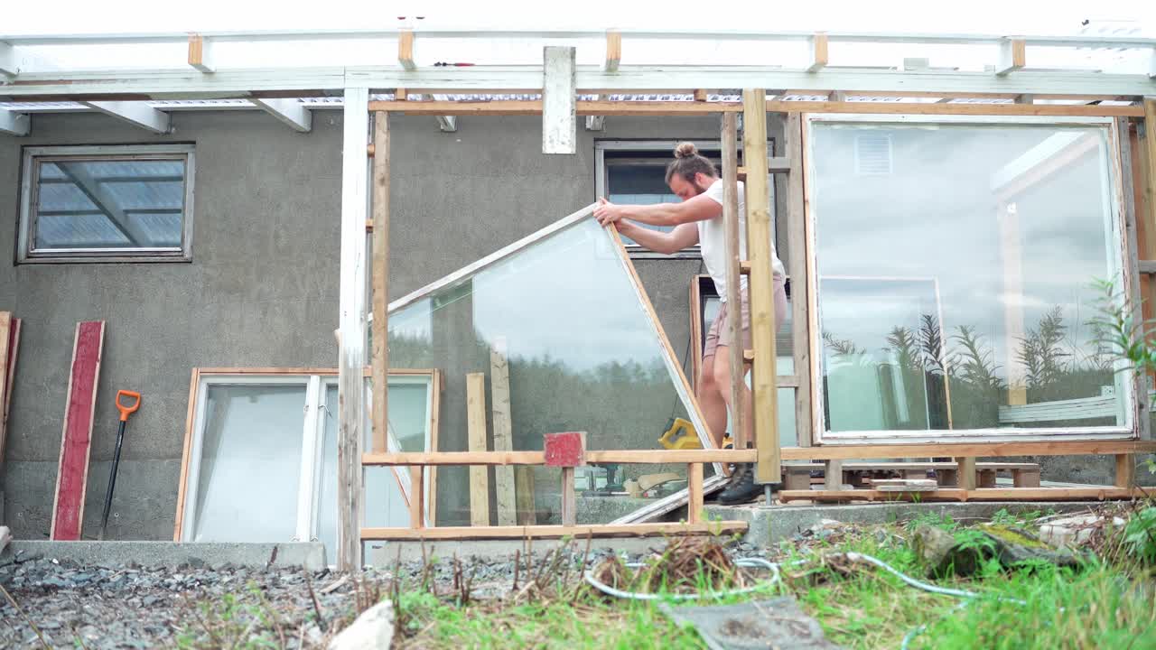 Un uomo sta assemblando i pannelli di vetro per una finestra di serra a Indre Fosen, contea di Trondelag, Norvegia - Inquadratura statica