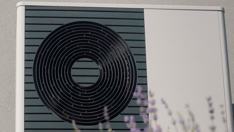 the external unit of the heat pump against the wall of a private house. lavender blooms in the foreground.