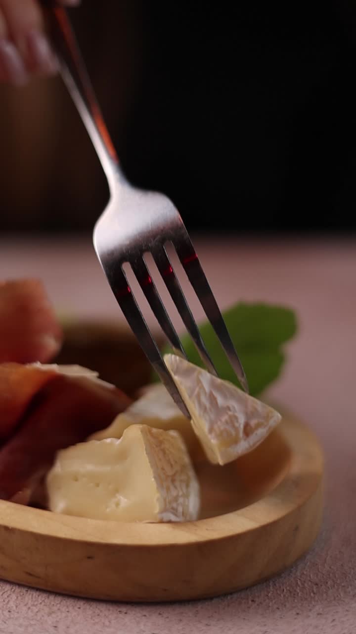 mujer comiendo queso camembert y aperitivo de jamón