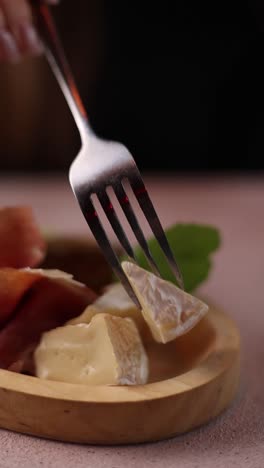 woman eating camembert cheese and ham appetizer