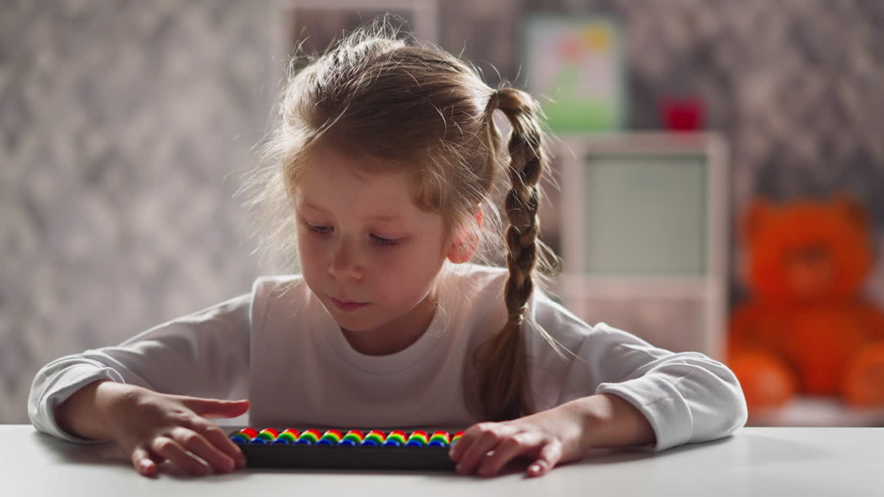 Spokojna dziewczynka z liczydłem rozwiązuje zadania, siedząc przy biurku.