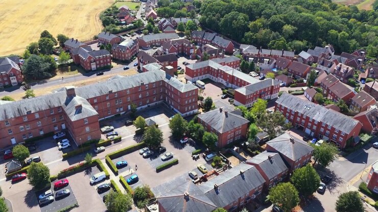 Veduta aerea da drone di Knowle Village vicino a Fareham, nell'Hampshire, caratterizzata da ex edifici ospedalieri vittoriani in mattoni rossi riconvertiti e moderne abitazioni residenziali circondate da campi verdi