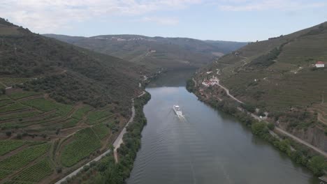 aerial view of the wine town of pinhão portugal , drone moving forward over the river douro showing the vines plantations and a tourist ship going down the river