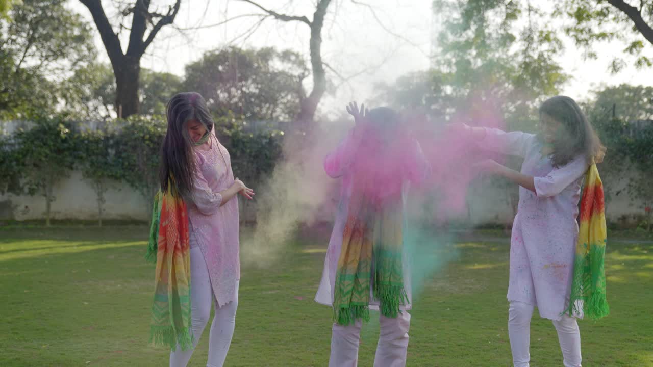 Donne indiane che lanciano i colori Holi su un uomo.